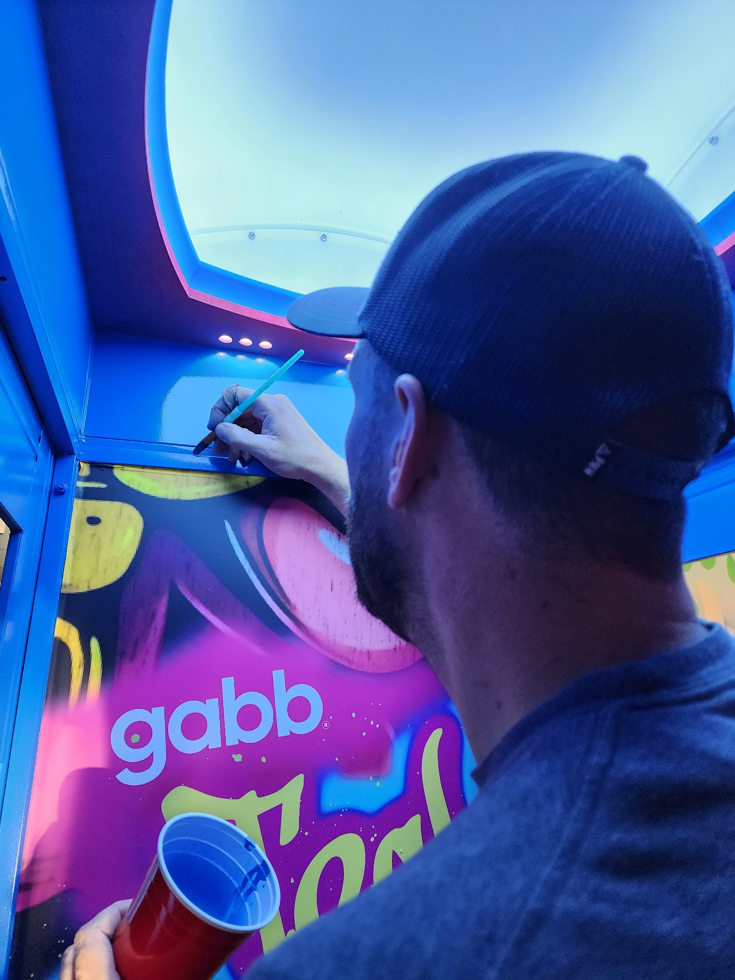 Hand-finishing the booth interior over the "Tech Rebel" graffiti mural