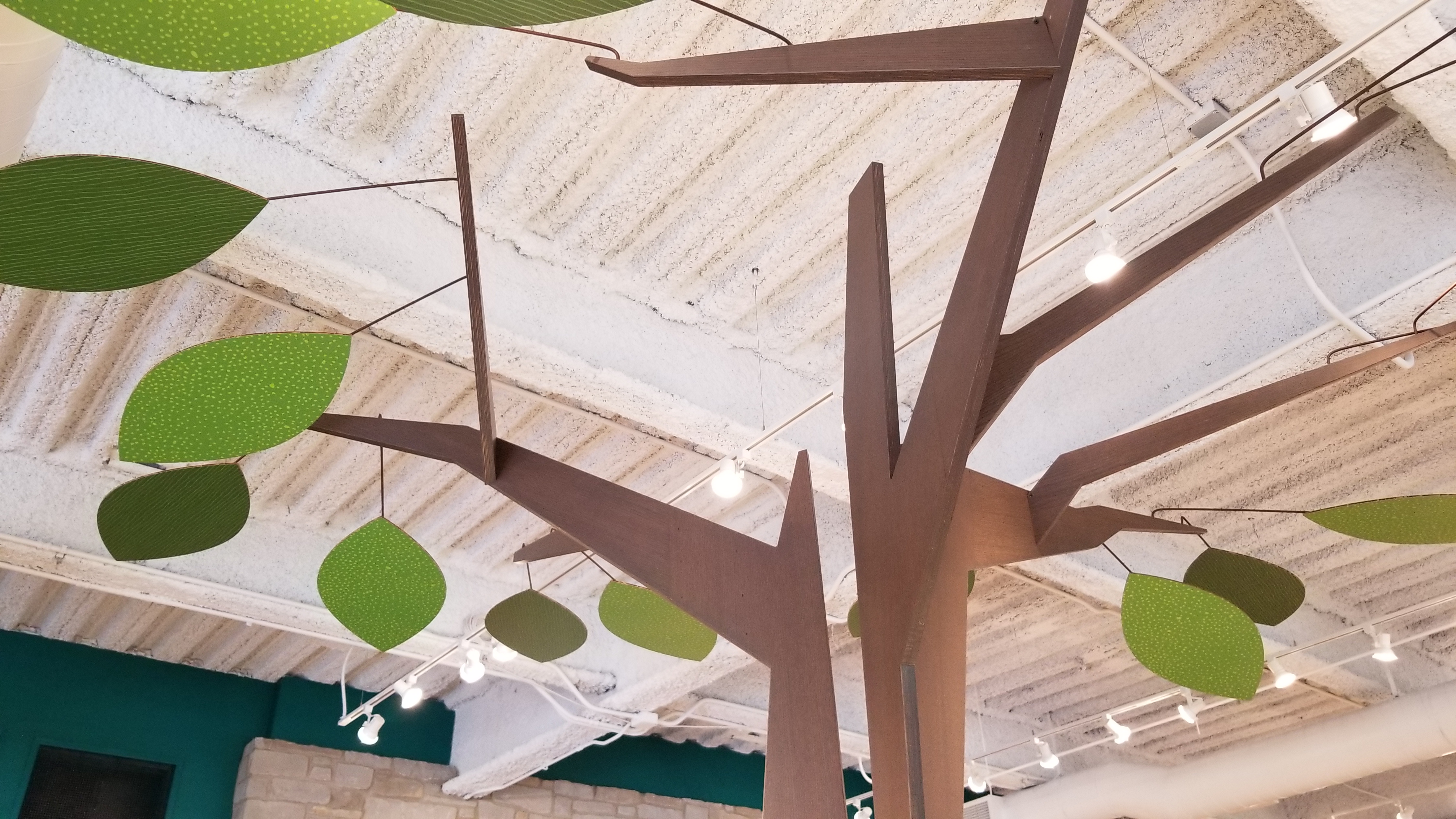A built tree canopy, felt leaves floating across the exposed ceiling