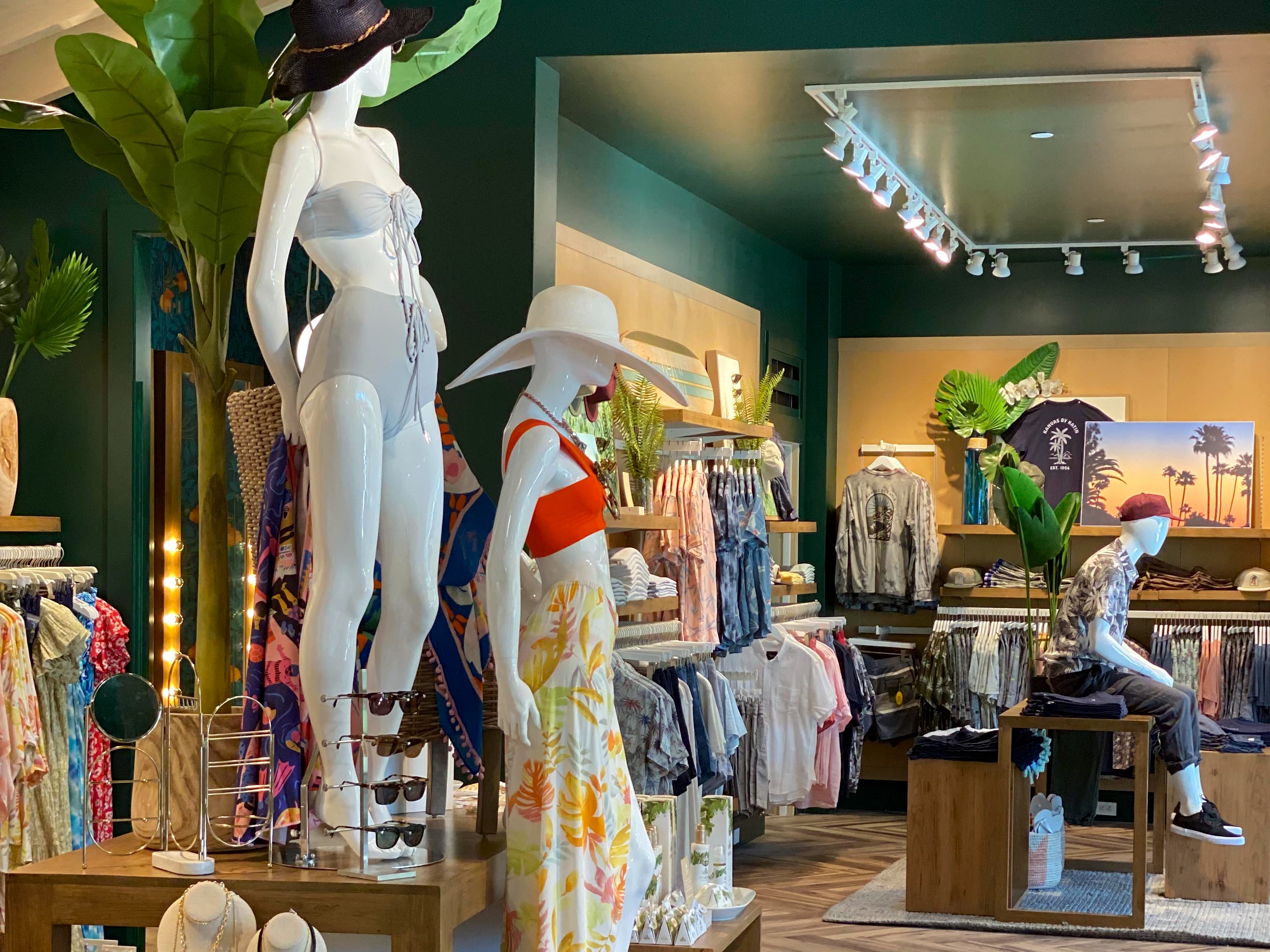 The sales floor — deep green walls, herringbone wood, and elevated mannequin platforms