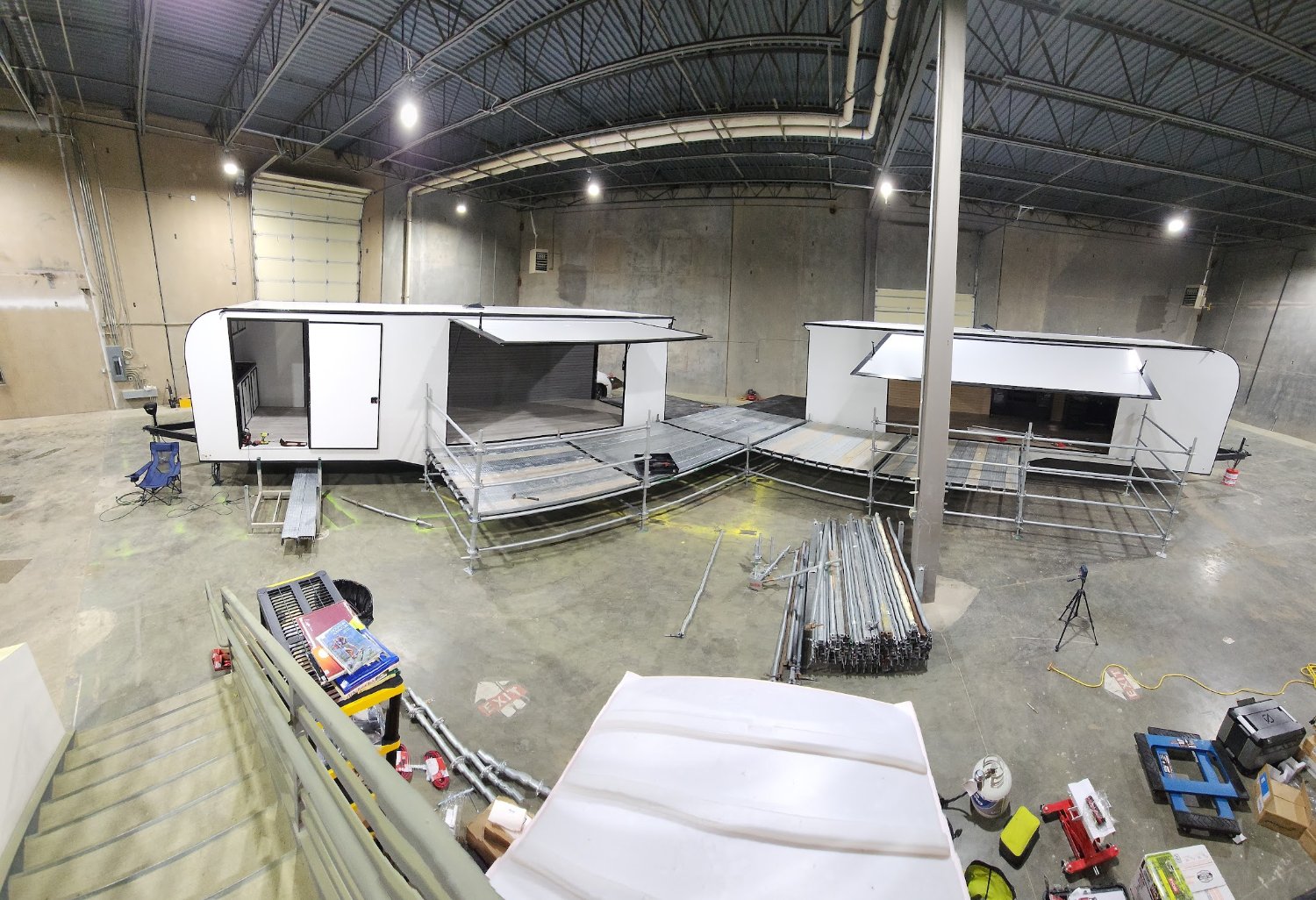 Two trailers mid-build in Treble20's shop — sidewalls open, decks and railings going in before they hit the road